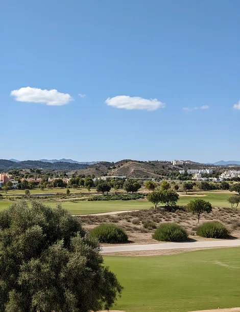 Calles del campo de golf entre olivos, con las colinas al fondo