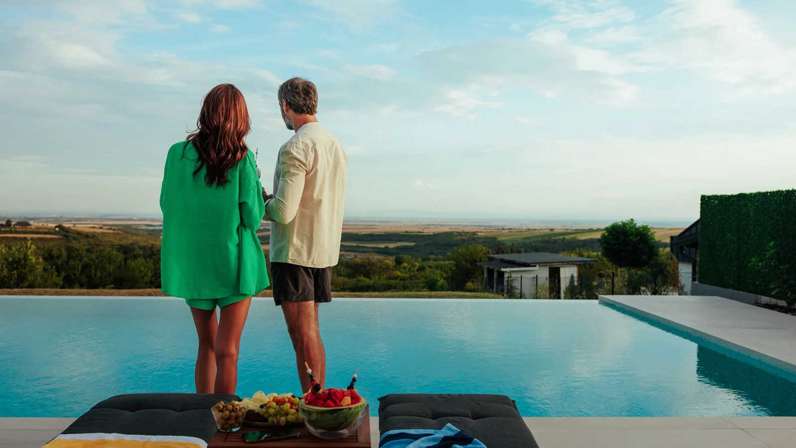 Una pareja junto a una piscina desbordante contempla el paisaje